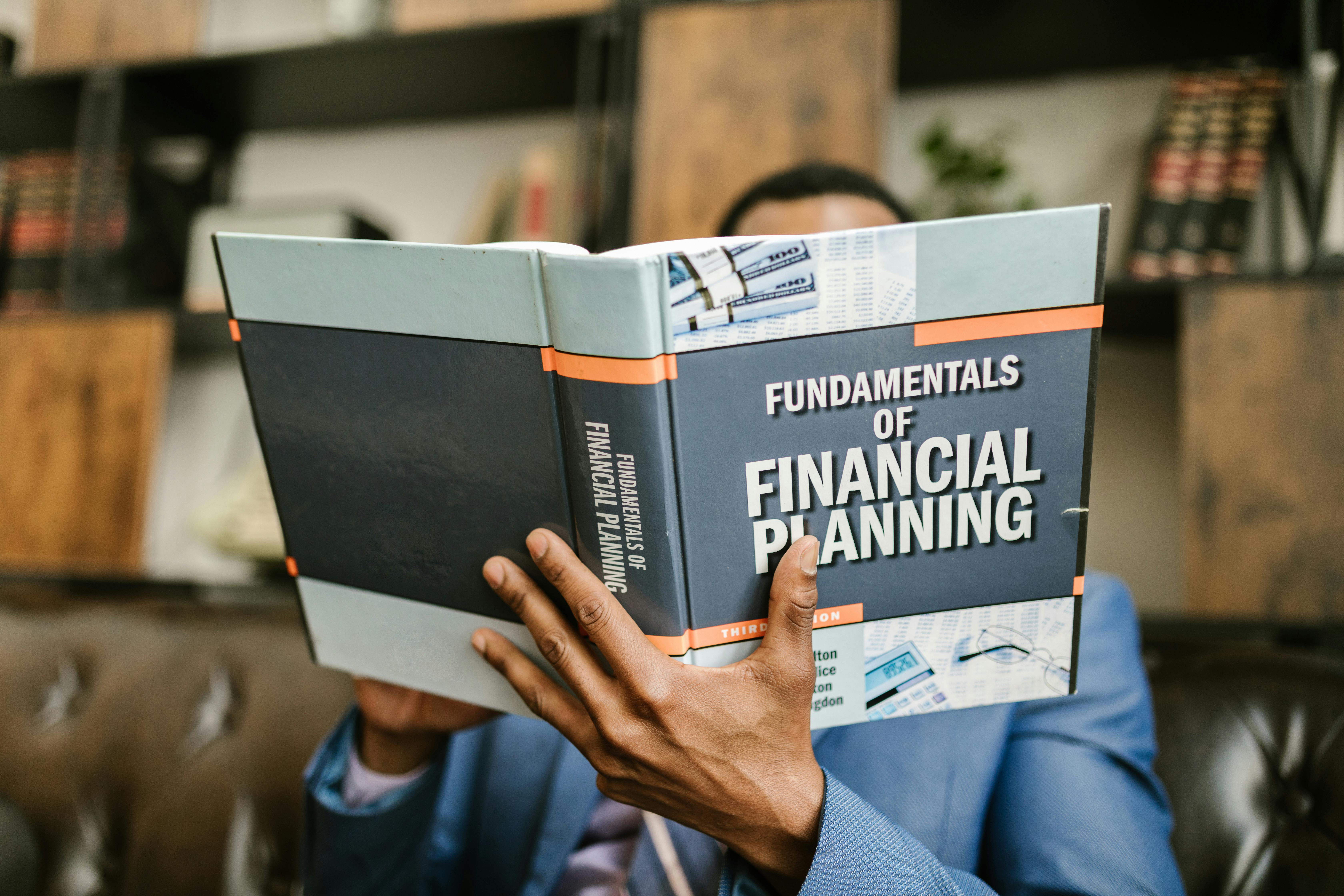 Book in a person's hands, titled The Fundamentals of Financial Planning